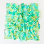 A crumpled square Playsilk, crafted from natural materials, features a green and blue scallop pattern on a white background—perfect for open-ended toys and imaginative play.